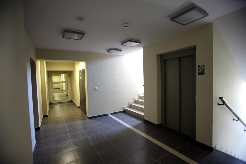 Klatka schodowa i korytarz starannie wykończony, podłogi wyłożone płytkami w kolorze czarnym ze ścianami w kontrastowym, białym kolorze
