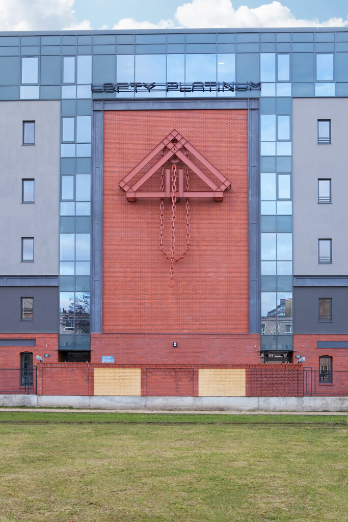 Ozdobny element konstrukcji stalowej z łańcuchem, nad nim napis Lofty Platinum, na ścianie budynku